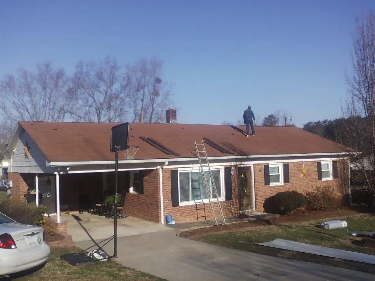 Roofer stripping a shingle roof on a brick ranch before metal panels in Happy Jack