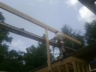 Carpenter setting a ridge beam over a new addition frame — Ice Dam Removal by Roofing Brothers in Happy Jack