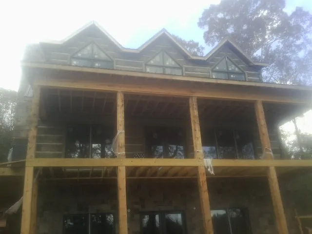 Dormers and porch framing on a large log home under construction — Roof Coating work by our crew in Happy Jack