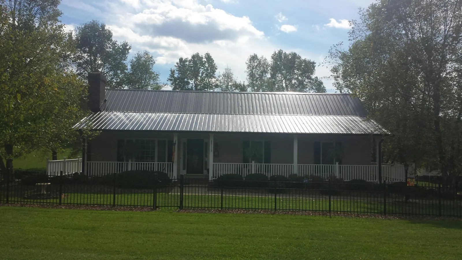 Gray metal roof on a brick ranch with a full width front porch — Gutter Guard Installation work by our crew in Happy Jack