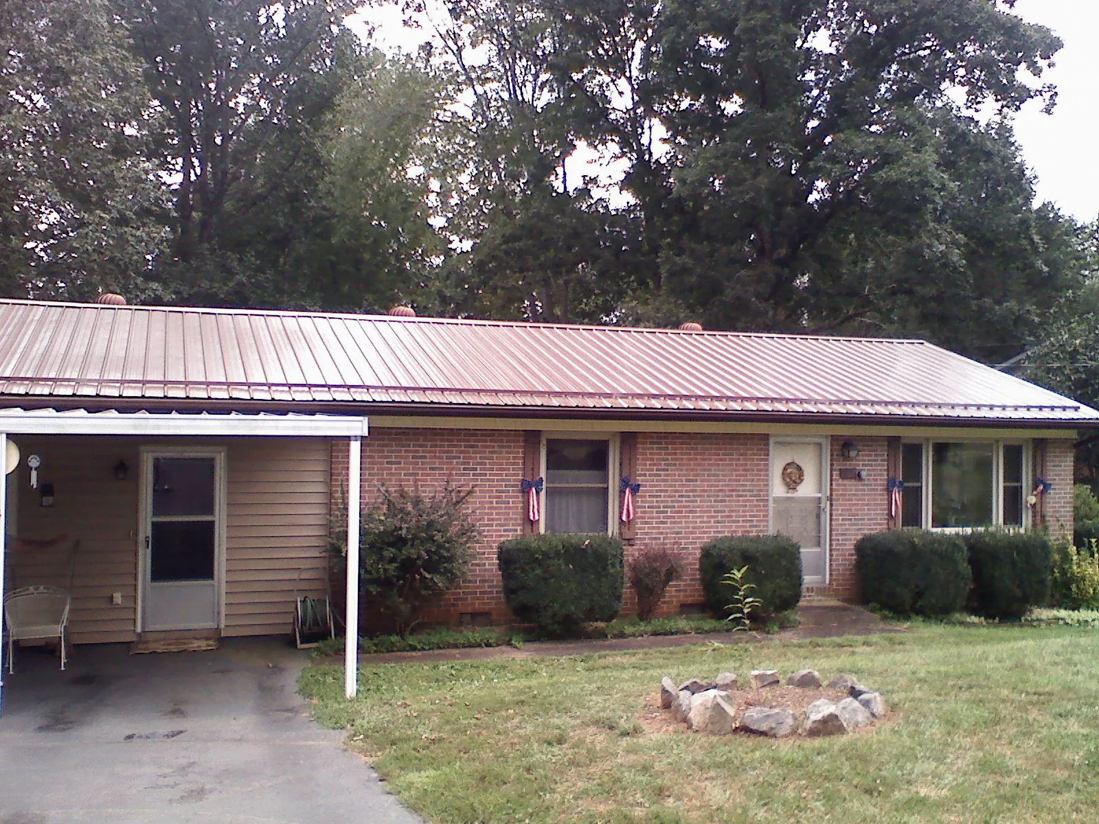 Bronze metal roof and carport on a brick ranch home — Roof Repair work by our crew in Happy Jack