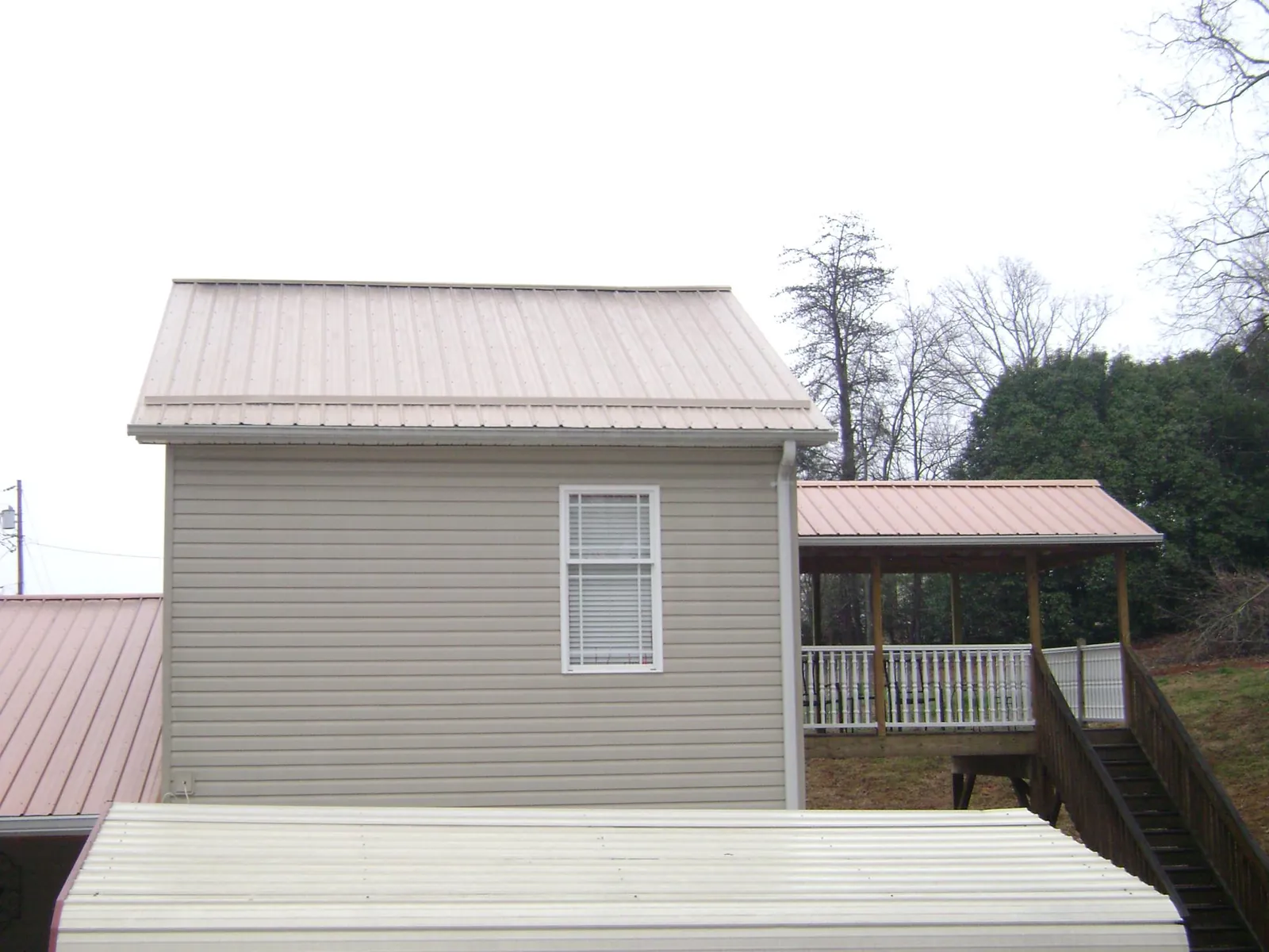 Tan metal roofs on a two story addition and attached porch, from a Roof Replacement job in Happy Jack