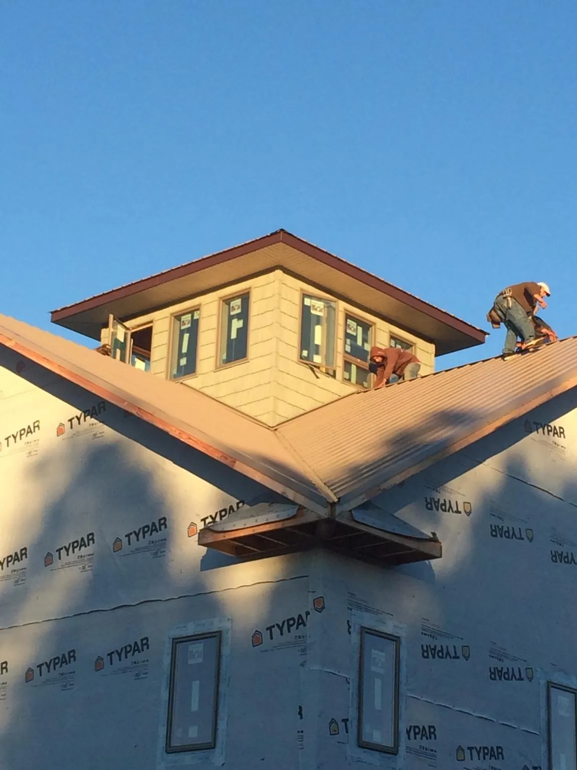 Roofers working around a rooftop cupola on a new metal roof at sunset — Roof Waterproofing in Happy Jack by Roofing Brothers